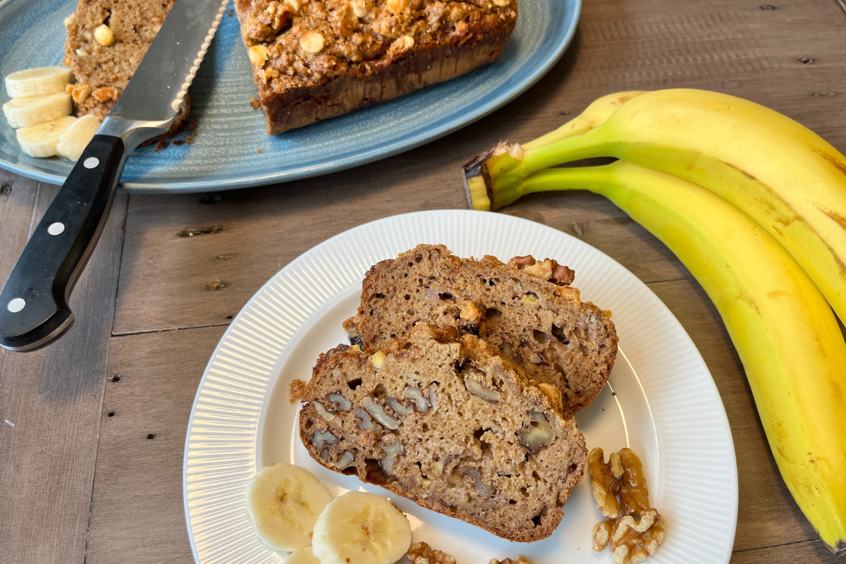 Gluten free chocolate walnut banana bread 2 slices on a plate with bananas and half a loaf